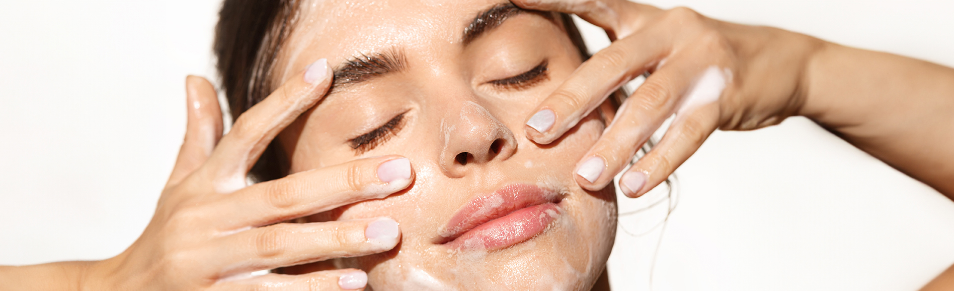 Frau wäscht ihr Gesicht mit Reinigungsschaum in Nahaufnahme.